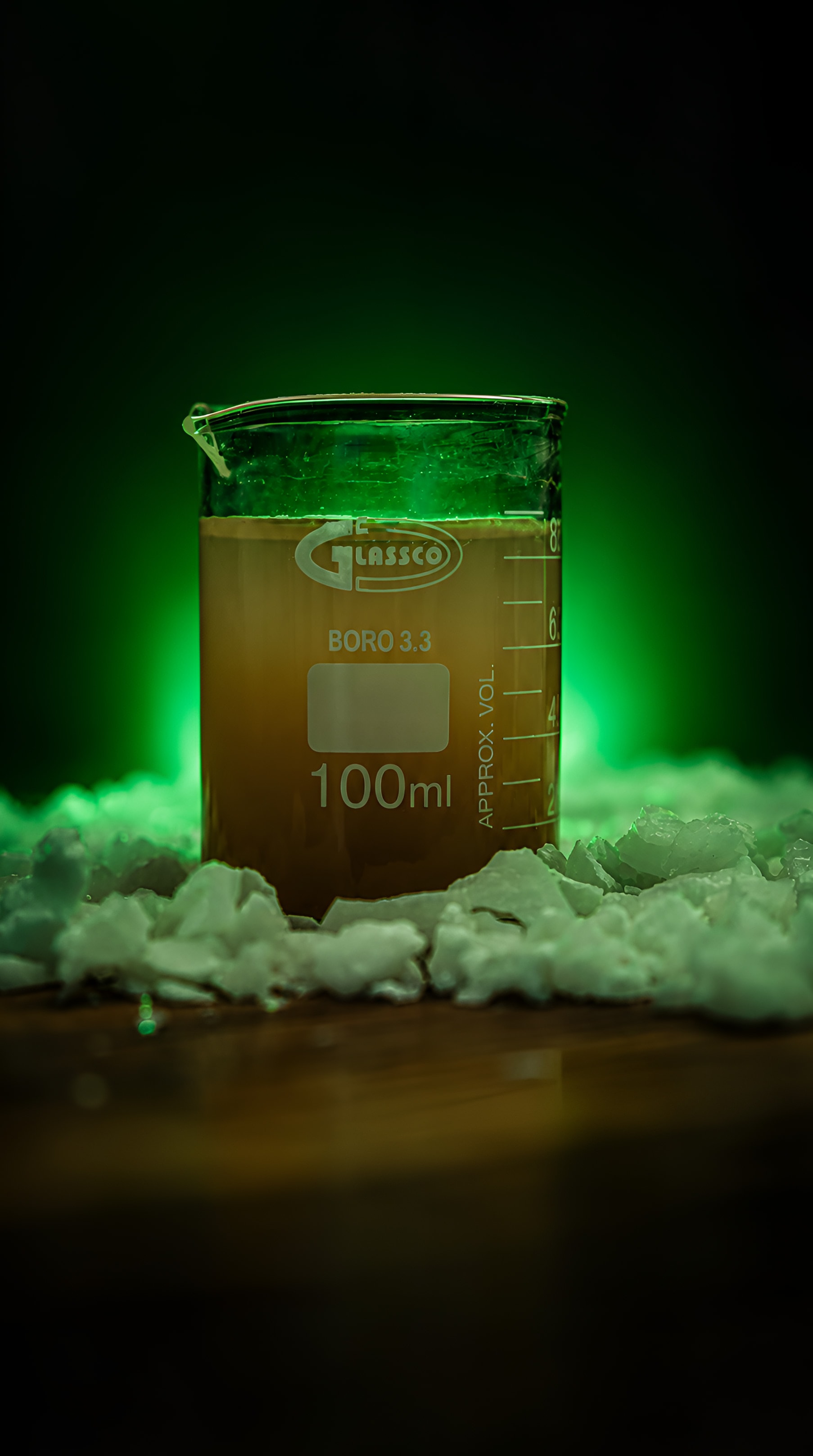 A beaker of aluminium sulfate solution on crystals of the product, lit green