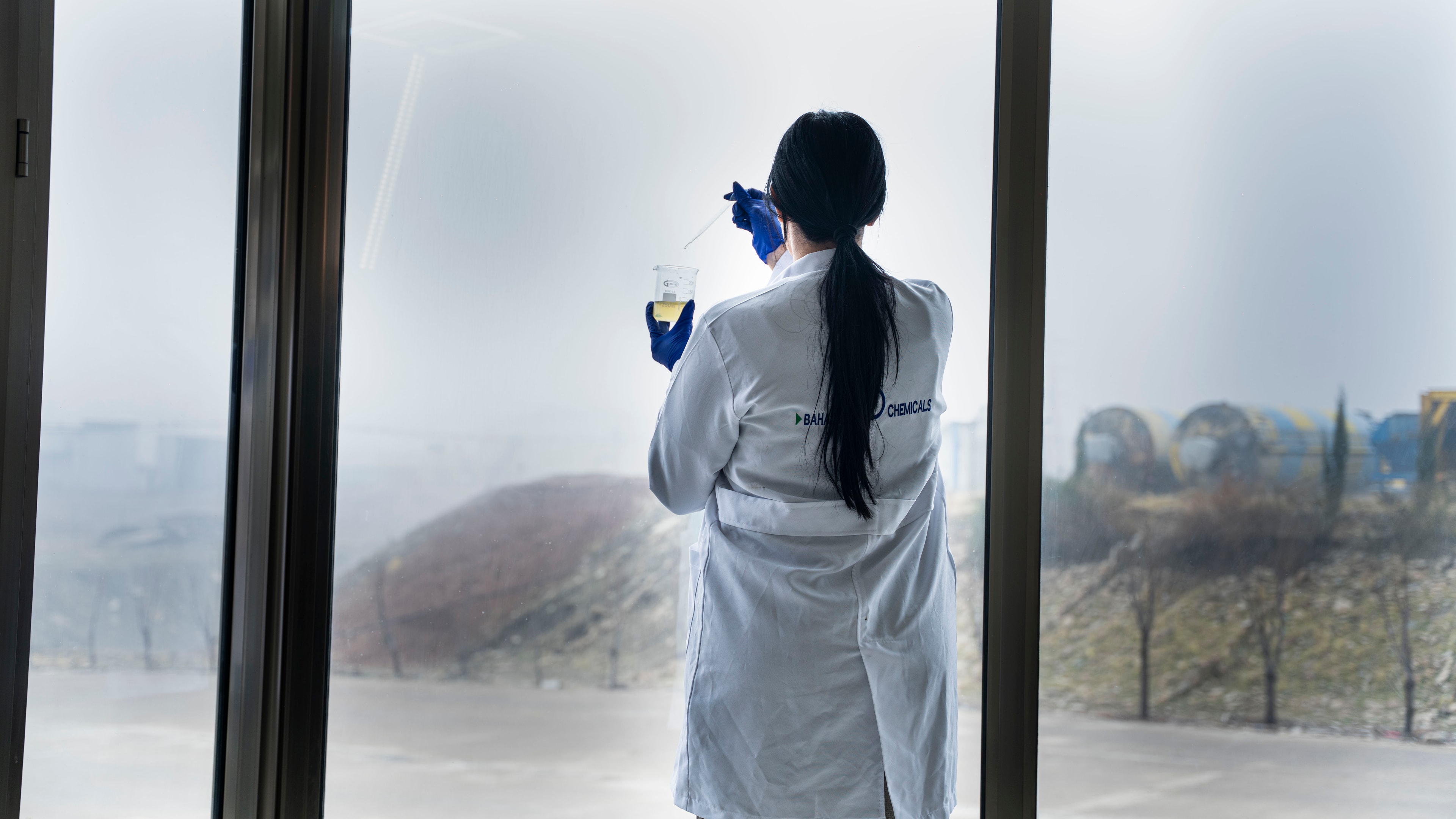A chemist at the laboratory window, holding a sample up to the light