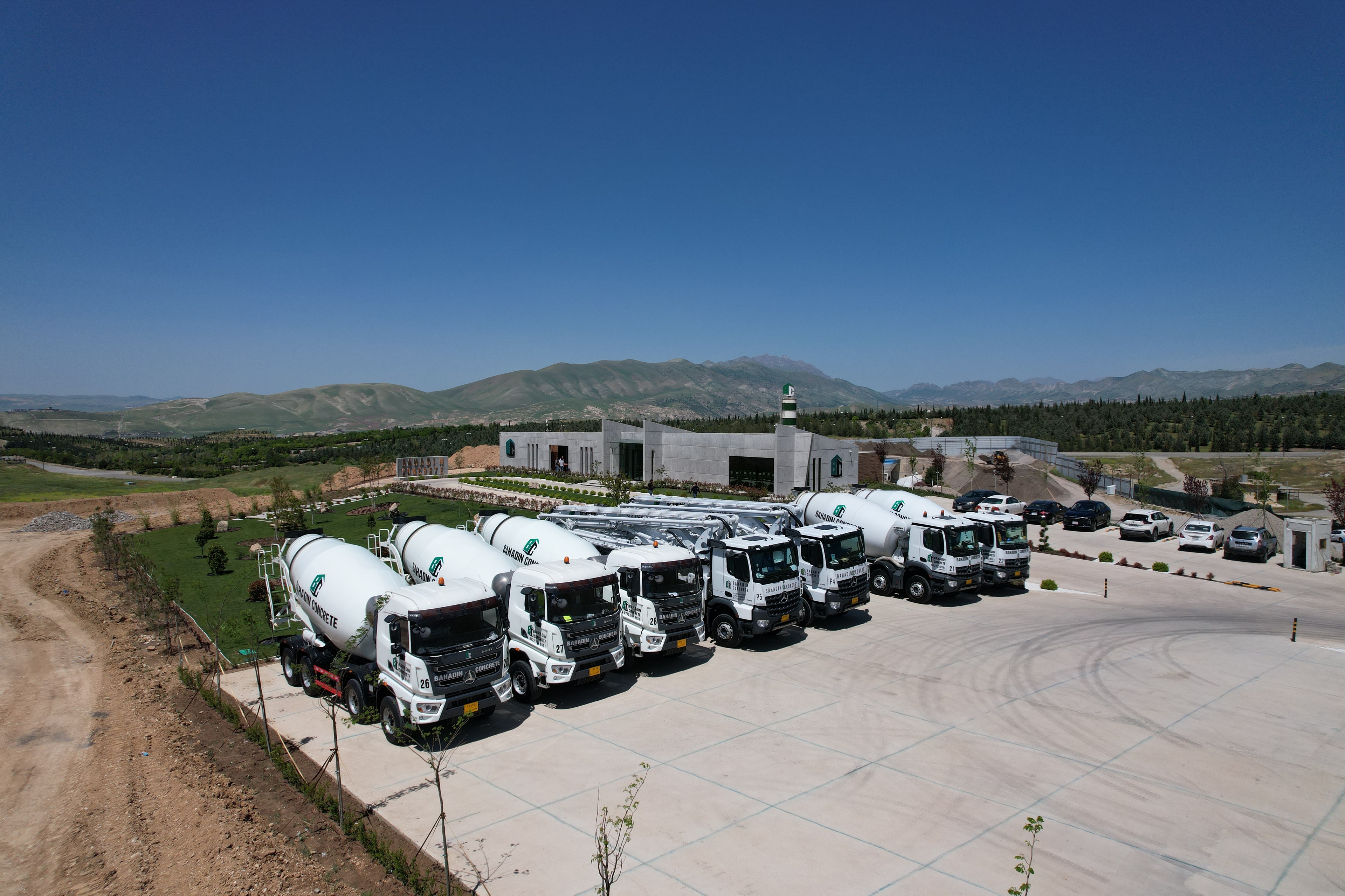 Bahadin Concrete's mixer trucks lined up outside the plant, mountains behind