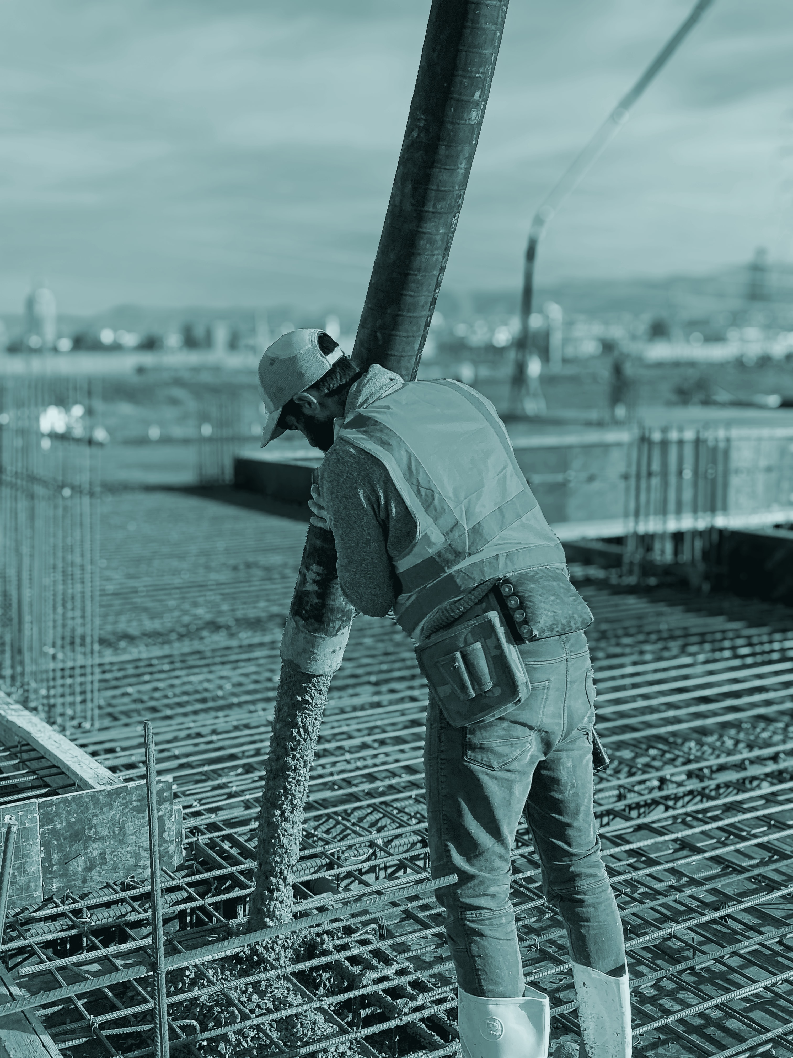 A worker guiding a concrete pump hose over steel reinforcement