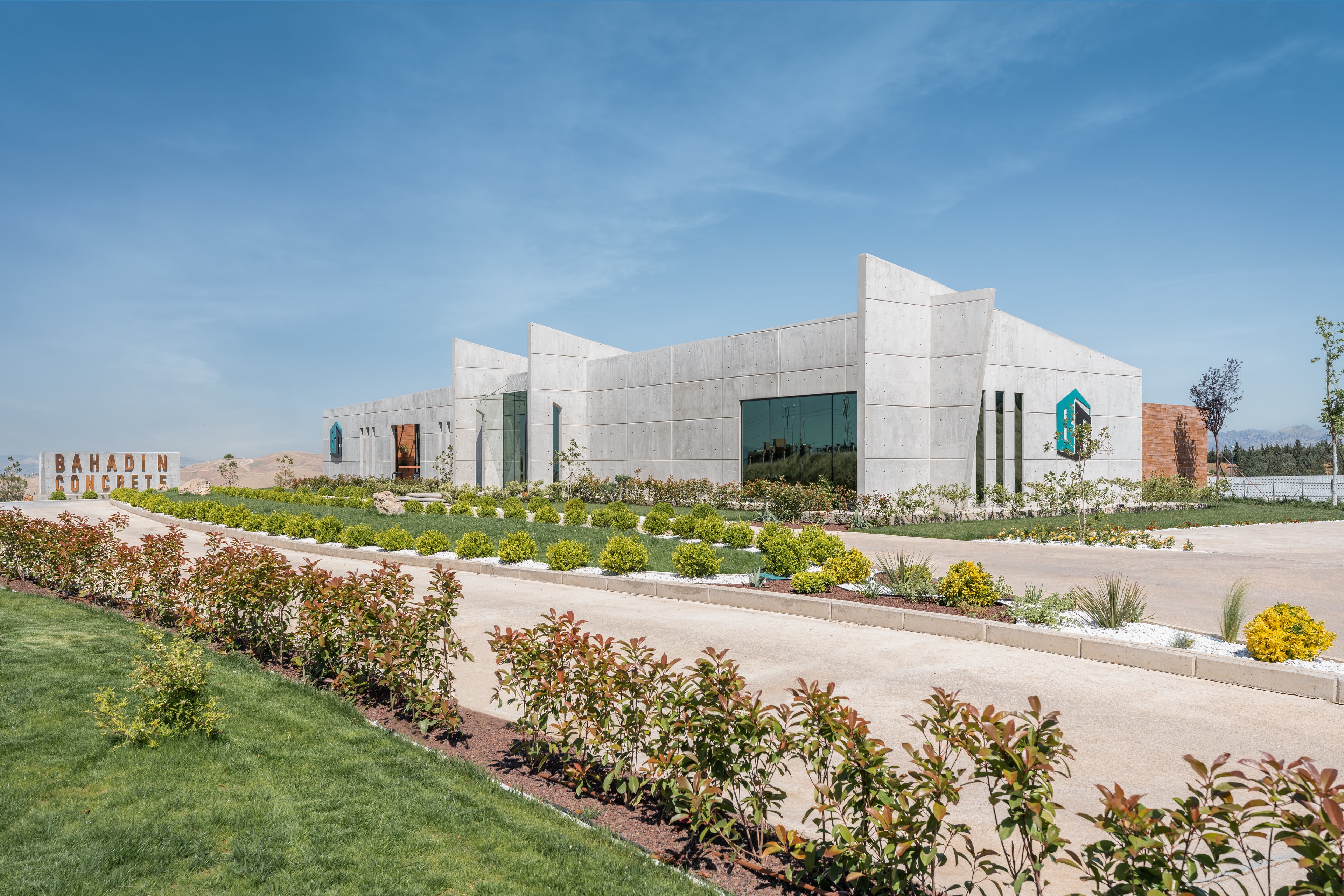 The Bahadin Concrete headquarters by day: a concrete building behind landscaped gardens under a blue sky